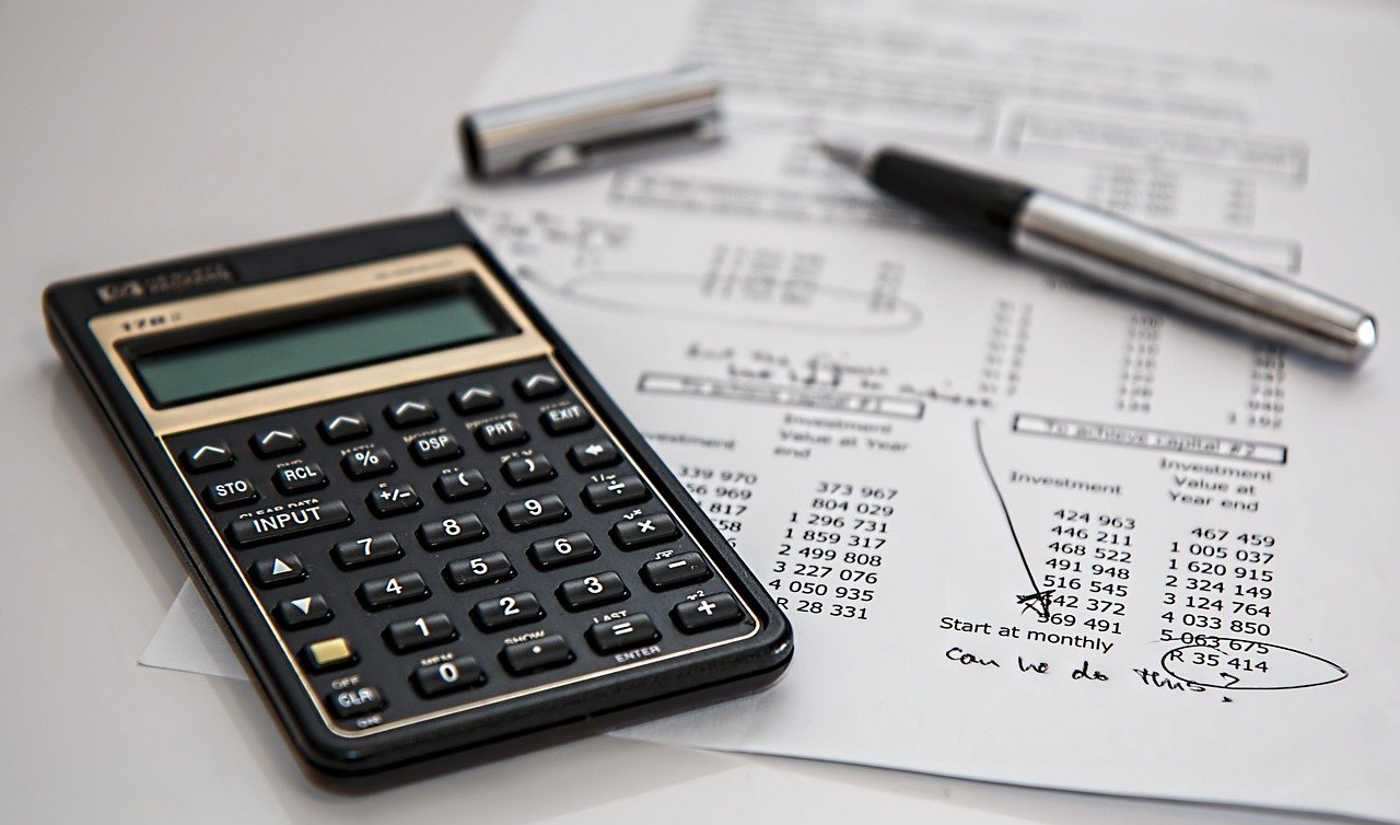 A calculator and pen on financial documents, representing careful consideration of coverage com auto insurance costs.